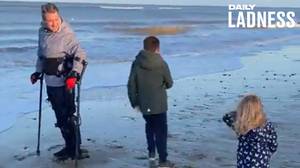 瘫痪的人使用exoskeleton在第一次和孩子一起在海滩上行走