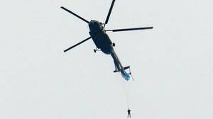 慢胎陷入困境后，跳伞运动员从直升机悬挂着