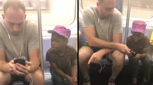 纽约地铁乘客让可爱的小男孩在手机上玩耍