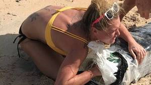 警察在追捕的女人偷偷摸摸地从海滩上淹没了杂草