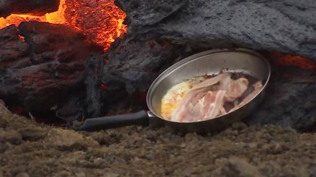 男人在活火山的Molten Lava上烹饪培根和鸡蛋
