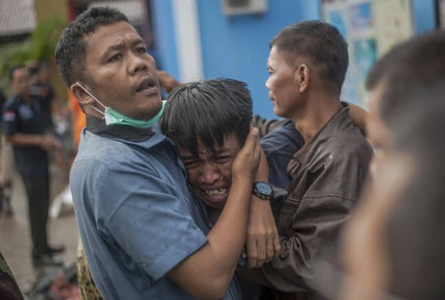 一名男子在印度尼西亚Carita的海啸受害者的尸体中确定自己的亲戚后做出了反应。信用：PA“width=