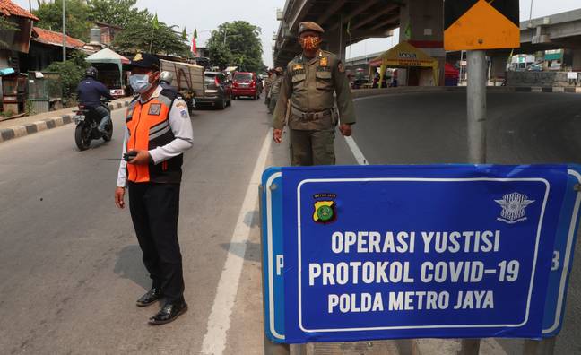 警察在警察检查点处守卫着大规模限制，以遏制印度尼西亚雅加达的冠状病毒爆发的传播。学分：PA