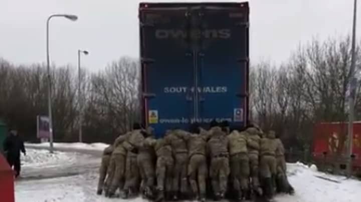 皇家海军陆战队有助于将卡在雪地上的卡车上山