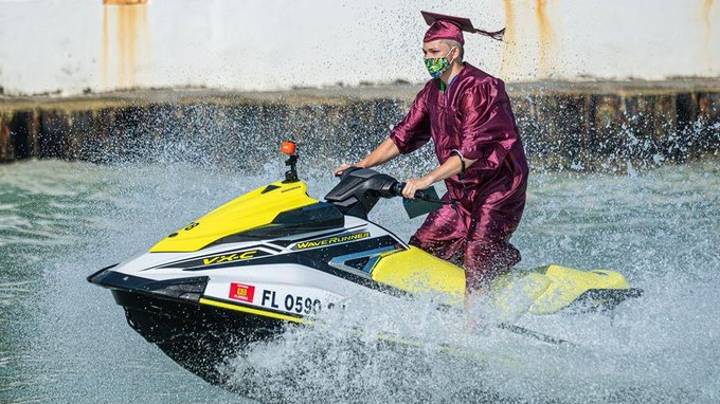 美国毕业的学生乘坐摩托艇从船上收集文凭