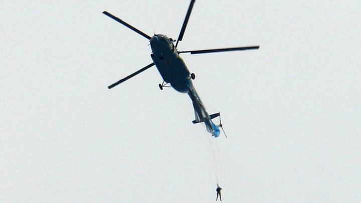 慢胎陷入困境后，跳伞运动员从直升机悬挂着“imgWitdh=