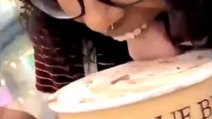 女人舔冰淇淋的开放式冰淇淋，然后将其放回商店冰箱里进行恶作剧