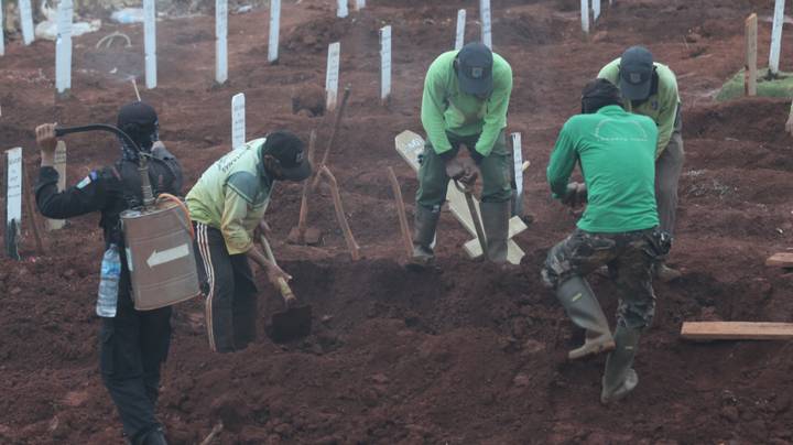 人们被抓到没有戴着爪哇的口罩来挖坟墓